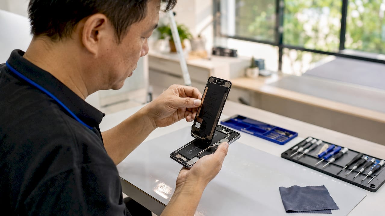 Hands removing smartphone screen ribbon cable