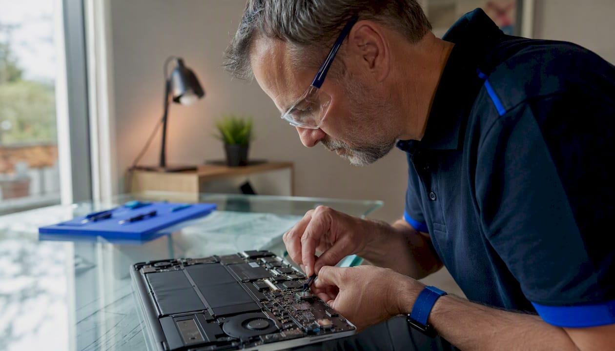 Technician unplugging laptop DC jack for repair