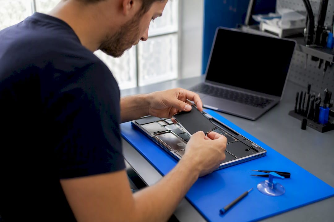 Technician hands removing MacBook trackpad