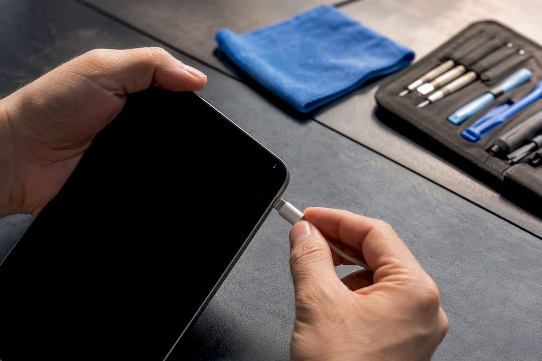 Technician inserting charging cable into iPad port
