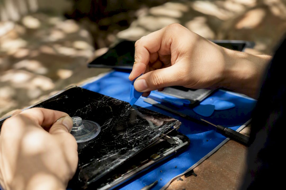 Hands repairing iPad screen with tools