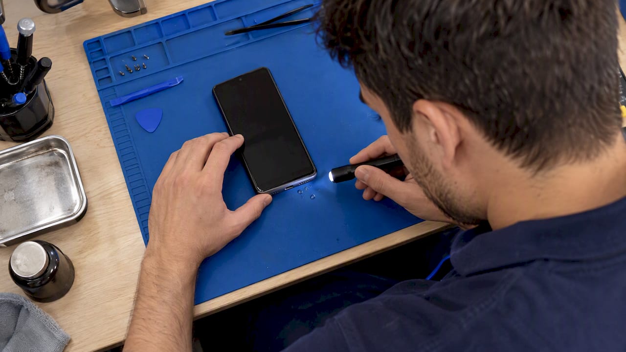 Technician inspecting a moisture-exposed Android charging port