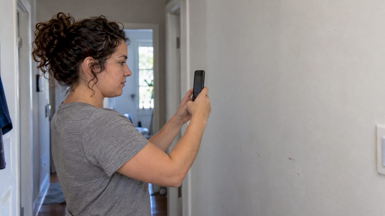Woman testing Android camera against plain wall
